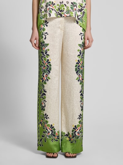 Frauenmodel trägt Wide Leg Pants aus Viskose-Mix mit Eingrifftaschen von Marc Cain in Creme mit grünem, floralem Muster, Loose Fit, Ganzkörperansicht von vorne. Bund elastisch, französische Eingrifftaschen, Stretch-Anteil, Bundweite 38 cm, Innenbeinlänge 77 cm.