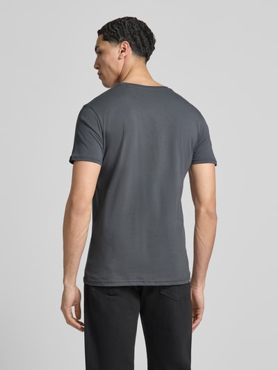 Männermodel trägt T-shirt mit Label-Details Modell 'BASIC' von Alpha Industries, puur katoen, recht model, ronde hals, ruglengte maat M 67 cm, Ganzkörperansicht Rückansicht.