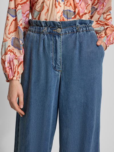 Frauenmodel trägt Hose aus Lyocell mit Tunnelzug Modell 'REESE' von SUNCOO PARIS, blau, Wide Leg, Detailaufnahme Vorderansicht.