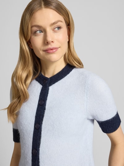 Frauenmodel trägt Regular Fit Cardigan aus Woll-Alpaka-Mix Modell 'Sanoura' von Samsøe Samsøe in Hellblau mit dunkelblauen Akzenten, Strick-Optik, kurze Ärmel, Rundhalsausschnitt, durchgehende Knopfleiste, Nahaufnahme Oberkörper.