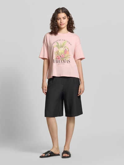 Frauenmodel trägt Boxy Fit T-Shirt aus reiner Baumwolle Modell 'LUCY' von Only, Optik: Unifarben, Motiv-Print vorne und Rücken-Print, Rundhals, Kurzarm, Ganzkörperansicht von vorne.