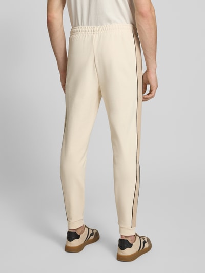 Mężczyznę model nosi Regular Fit Sweatpants aus reiner Baumwolle von Lacoste, dwukolorowy, krój regular fit, naszywka z logo, elastyczny ściągacz z regulacją szerokości, wpuszczane kieszenie boczne, wykończenie: dzianina dresowa, materiał: czysta bawełna, widok całej sylwetki z tyłu.