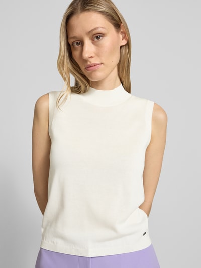 Frauenmodel trägt Stricktop aus Lyocell-Mix mit Stehkragen von GUIDO MARIA KRETSCHMER WOMAN, Slim Fit, Label-Detail, Nahaufnahme Oberkörper. Rückenlänge bei Größe 36: 49 cm, cremefarbene, glatte Textur.