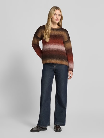 Frauenmodel trägt Strickpullover im Allover-Look mit Rundhalsausschnitt von MORE & MORE in Braun-Beige-Rot, Relaxed Fit, Material-Mix mit Alpaka-Anteil, Ganzkörperansicht von vorne.
