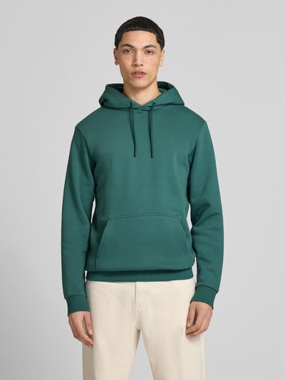 Männermodel trägt Regular Fit Hoodie aus Baumwoll-Mix Modell 'CERES' von Only & Sons, Optik: Unifarben, Kängurutasche, Ganzkörperansicht von vorne.