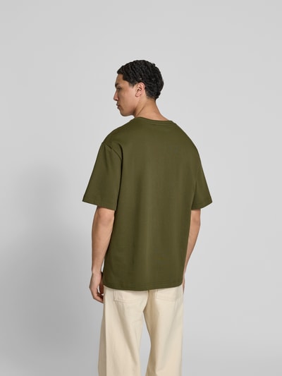 Männermodel trägt T-Shirt mit Rundhalsausschnitt von Filippa K in Olivgrün, reine Baumwolle, Relaxed Fit, Ganzkörperansicht Rückansicht.
