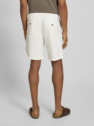Mężczyzna nosi Regular Fit Chinoshorts aus Baumwoll-Leinen-Mix Modell 'BRODY' von SELECTED HOMME, kolor jednolity, detal metki, szlufki, kieszenie boczne i tylne z guzikiem, materiał flammgarn, bawełna-len; widok całej sylwetki z tyłu.