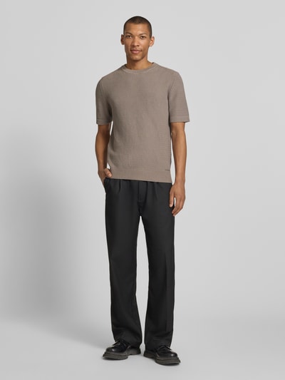 Männermodel trägt Relaxed Fit Strickpullover aus reiner Baumwolle Modell 'SAFFON' von HUGO, unifarben, Waffelstrick, Ganzkörperansicht von vorne.