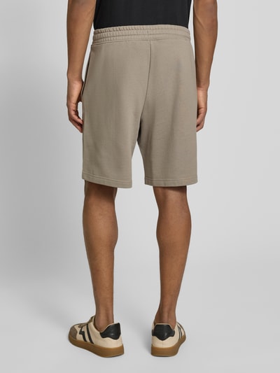Męski model nosi Regular Fit Sweatshorts aus reiner Baumwolle Modell 'DAYONO' von HUGO, jednokolorowy, krój regular fit, nadruk z logo, elastyczny ściągacz z tunelem, boczne wpuszczane kieszenie, dzianina dresowa, bawełna, całkowity widok z tyłu.