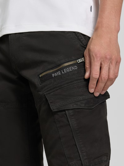 Mannenmodel draagt Slim Fit broek uit katoenmix in cargo-look van PME Legend, zwart met zilverkleurige ritssluiting, detailopname rechterdij. Heren, knoop- en ritssluiting, bandwijdte bij maat 32/32: 44 cm, binnenbeenlengte bij maat 32/32: 80 cm.
