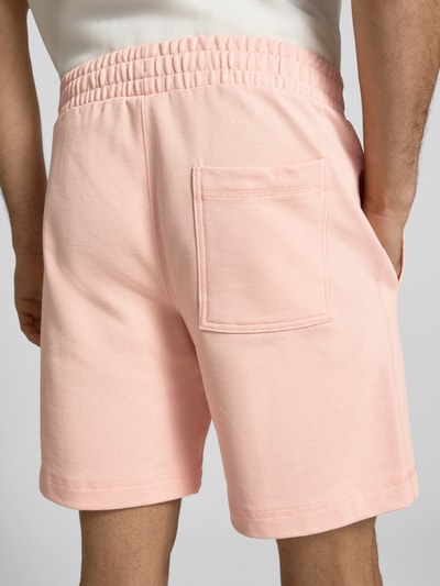 Männermodel trägt Sweatshorts mit Stitching Modell 'KARL' von Jack & Jones, hellrosa Baumwoll-Mix, elastischer Bund, Ganzkörperansicht Rückansicht.