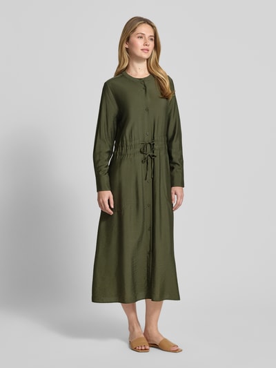 Frauenmodel trägt Relaxed Fit Midikleid aus Viskose-Mix Modell 'Mariela' von Guido Maria Kretschmer WOMAN in Olive mit Tunnelzug, rundem Halsausschnitt, Knopfleiste und aufgesetzten Taschen, Ganzkörperansicht von vorne.