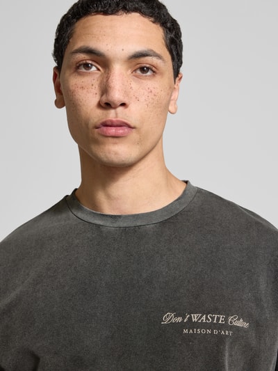 Männermodel trägt Regular Fit T-Shirt aus Baumwoll-Mix von Don't Waste Culture, Statement-Print, dunkle Farbe, Nahaufnahme Oberkörper.