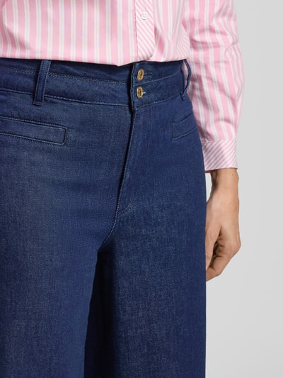 Frauenmodel trägt Jeans mit Eingrifftaschen von More & More, dunkelblauer Baumwoll-Elasthan-Mix, lockerer Schnitt, Nahaufnahme Oberkörper.