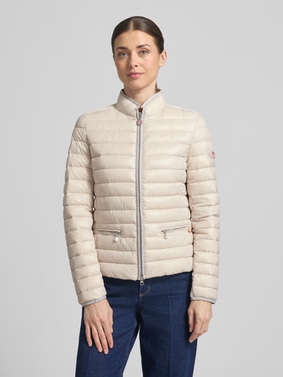 Frauenmodel trägt Steppjacke mit Reißverschlusstaschen Modell 'SISTER JUDY' von Frieda & Freddies in Beige, horizontal gesteppt, Stehkragen, Silberdetails, Slim Fit, Ganzkörperansicht von vorne. Rückenlänge 56 cm, Schulterbreite 41 cm, Brustweite 47 cm, Ärmellänge 61 cm.