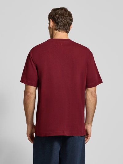 Männermodel trägt dunkelrotes Relaxed Fit T-Shirt aus reiner Baumwolle Modell 'MAARKOS HEAVY WEIGHT' von ARMEDANGELS, Ganzkörperansicht Rückansicht. Herren T-Shirt