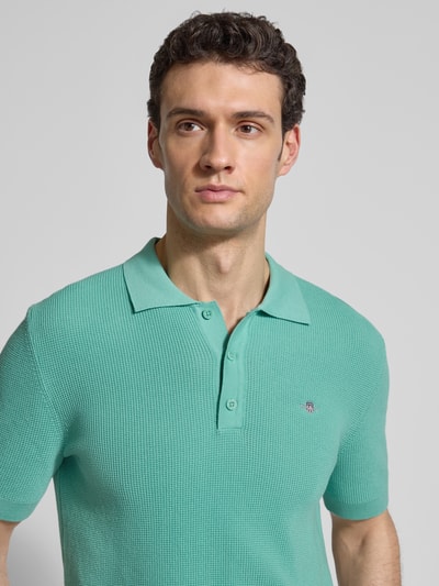 Männermodel trägt Regular Fit Poloshirt mit Label-Stitching von Gant aus reiner Baumwolle, Polokragen, Nahaufnahme Oberkörper.