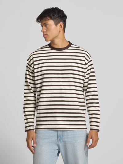 Männermodel trägt Regular Fit Longsleeve aus reiner Baumwolle mit Streifenmuster von JACK & JONES, weiße Basis mit braunen Streifen, Ganzkörperansicht von vorne. Rückenlänge bei Größe M 70 cm, Rundhalsausschnitt, legere Passform.