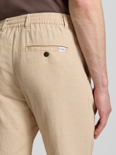 Männermodel trägt Regular Fit Hose aus Baumwoll-Leinen-Mix Modell 'BRODY' von SELECTED HOMME, sandfarben, Melange-Optik, Detailaufnahme.
