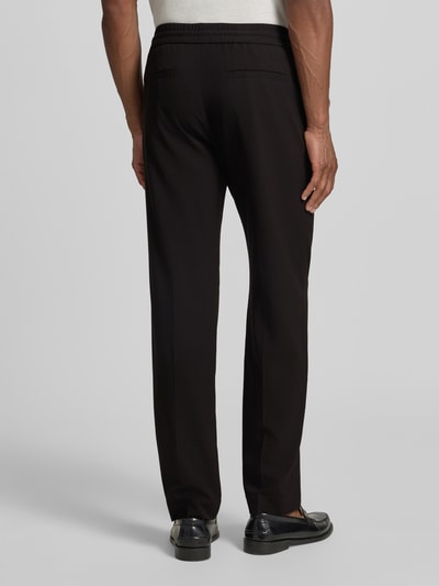 Männermodel trägt Relaxed Fit Sweatpants mit Viskose-Anteil von Lindbergh, Schwarz, Elastischer-Material-Mix, Bügelfalten, Ganzkörperansicht Rückansicht. Bundweite in Größe M beträgt 41 cm, Innenbeinlänge 79 cm.