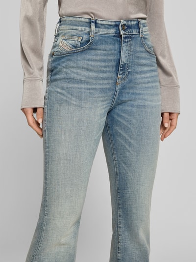 Frauenmodel trägt Flared Fit Jeans mit Logo-Detail von Diesel aus Baumwoll-Mix, 5-Pocket-Design, Knopf-Reißverschluss, Nahaufnahme Oberkörper.