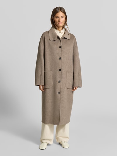 Frauenmodel trägt Wollmantel aus Woll-Mix von MYON in Taupe mit lockerer Passform und aufgesetzten Taschen, Ganzkörperansicht von vorne.