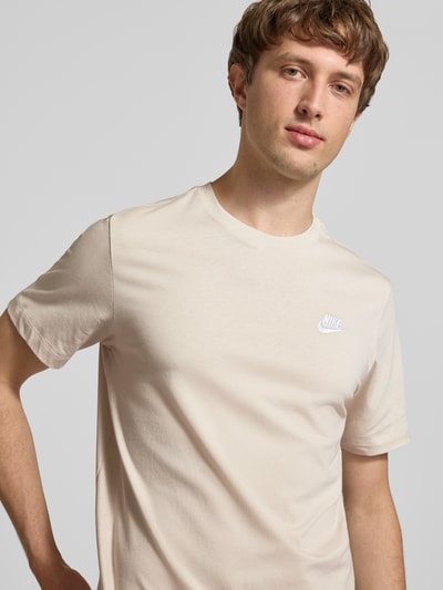 Männermodel trägt T-Shirt mit Label-Stitching von Nike in Beige, Reine Baumwolle, Regular-Fit, Rundhalsausschnitt, Nahaufnahme Oberkörper. Rückenlänge bei Größe M: 73 cm.