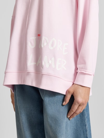 Frauenmodel trägt Oversized Sweatshirt mit Statement-Print und Rollsaum von Smith and Soul in Rosa aus Baumwoll-Mix mit Modal-Anteil, Nahaufnahme Oberkörper.