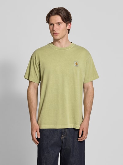 Männermodel trägt Herren T-Shirt mit Label-Detail Modell 'Nelson' von Carhartt Work In Progress aus Reine Baumwolle, Relaxed-Fit, Rundhalsausschnitt, dezentes Grün, strukturierte Oberfläche, Rückenlänge bei Größe M 72 cm, Ganzkörperansicht von vorne.