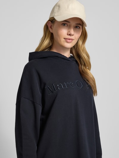 Kobiece modelka nosi Oversized Sweatkleid aus reiner Baumwolle od Marc O'Polo, efekt: jednolity kolor, krój oversized, długość midi, aplikacja z wyhaftowanym logo, napis z logo, długi rękaw z prążkowanym zakończeniem, wykończenie materiału: dzianina dresowa, materiał: bawełna, zbliżenie na górną część ciała