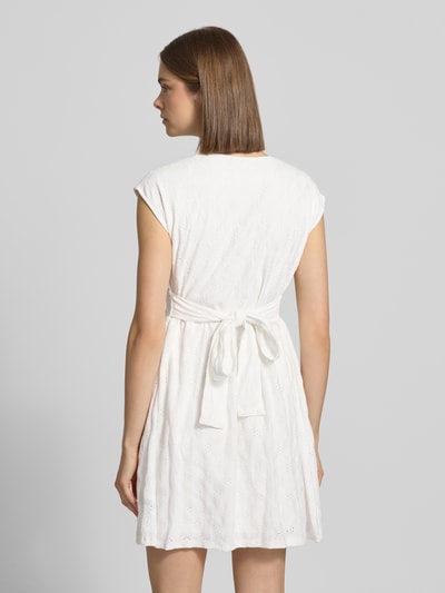 Frauenmodel trägt Kurzes Kleid mit V-Ausschnitt, Lochstickerei und großer Schleife von REVIEW, A-Linie, Material-Mix mit Stretch-Anteil, Rückenlänge 84 cm, Brustweite 42 cm, Ganzkörperansicht Rückansicht.