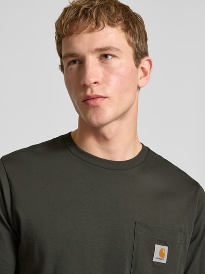 Männermodel trägt Regular Fit T-Shirt mit Logo-Patch von Carhartt Work In Progress, reine Baumwolle, Brusttasche, Nahaufnahme Oberkörper.