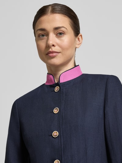 Vrouwenmodel draagt 'Slim Fit Blazer aus Leinen-Baumwoll-Mix' van WHITE LABEL in donkerblauw met roze staande kraag, knoopsluiting en opgestikte zakken, gemaakt van linnen-katoenmix, slim fit, borstwijdte 44 cm bij maat 36, mouwlengte 64 cm, ruglengte 71 cm. Close-up van het bovenlichaam.