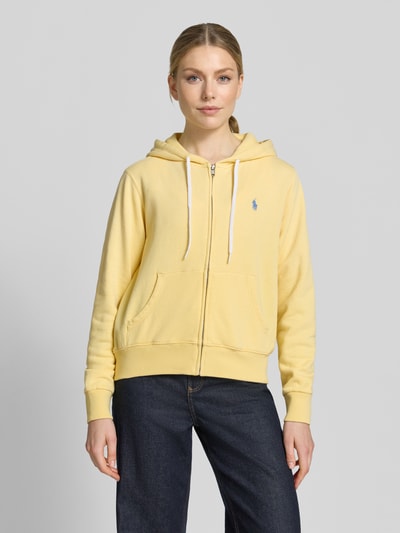 Modelka kobieca nosi Regular Fit Sweatjacke aus Baumwoll-Mix od Polo Ralph Lauren, bawełniana bluza z kapturem w kolorze żółtym, gładka faktura, długie rękawy, kieszenie, logo z przodu, widok całej sylwetki z przodu.