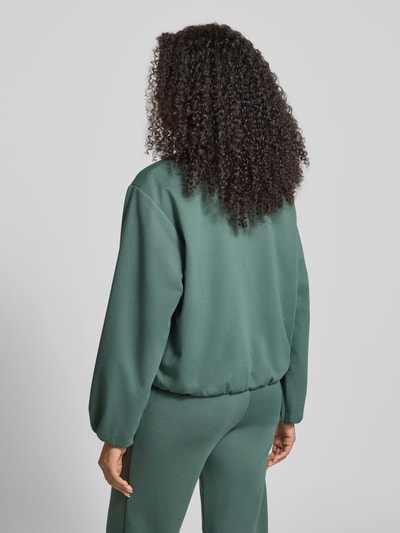 Kobiece model prezentuje Regular Fit Kurtka z dodatkiem wiskozy Model 'Nanni' od FREE/QUENT, elastyczna mieszanka materiałów, okrągły dekolt, zamek błyskawiczny, wpuszczane kieszenie, balonowy efekt, tył długości 55 cm w rozmiarze S, szerokość ramion 50 cm, szerokość klatki 57 cm, długość rękawów 57 cm; matowe, zielone powierzchnie, widok całej sylwetki z tyłu.