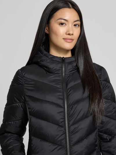 Modelka nosi Slim Fit Puffer Coat mit Steppnähten od Jake*s Casual, kolor jednokolorowy, stójka z kapturem, pikowanie, zamek błyskawiczny dwustronny, długi rękaw, proste wykończenie, kieszenie zapinane na zamek błyskawiczny, wykończenie materiału: pikowane. Zbliżenie na górną część ciała z przodu.