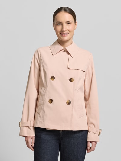 Kobiece modelka nosi Trenchcoat mit Knopfverschluss od MICHAEL Michael Kors, krój regular fit, jasnoróżowy, dwurzędowy, gładka faktura, kołnierz wykładany, guziki, Szerokość w rozmiarze S: 52 cm, długość pleców: 61 cm, długość rękawa: 63 cm, Szerokość w rozmiarze S ramion: 40 cm, zdjęcie całej sylwetki od przodu.