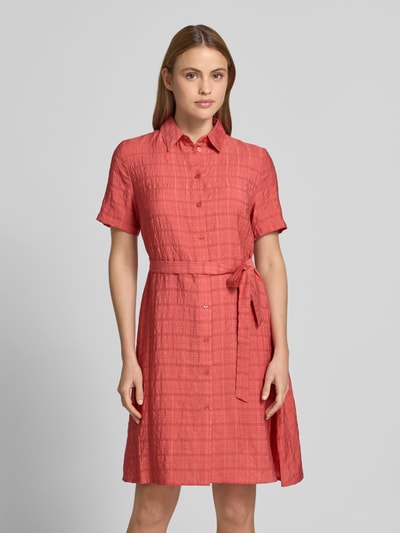 Vrouwenmodel draagt 'Hemdblusenkleid aus Viskose-Lyocell-Mix mit Bindegürtel' van Jake*s Casual, structuurpatroon, A-lijn, knielengte, overhemdkraag, mix van viscose en lyocell, strikceintuur, ruglengte maat 36 98 cm, borstwijdte maat 36 36 cm, mouwlengte maat 36 24 cm, effen zalmroze, voorkant volledig zichtbaar, ganzkörperansicht van voren.