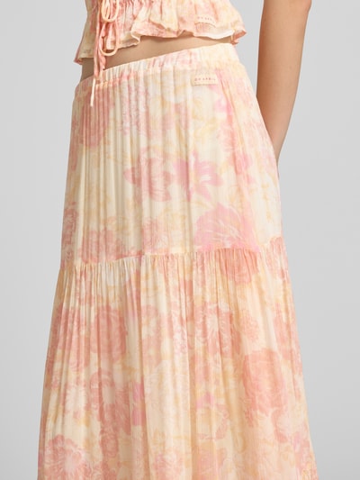 Frauenmodel trägt Maxirock aus Viskose im Stufen-Look Modell 'Caloa' von OH APRIL in Pastelltönen mit floralem Muster, Nahaufnahme Oberkörper.