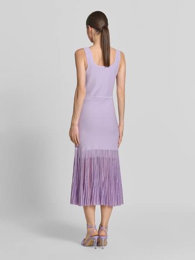 Frauenmodel trägt Strickkleid aus Rippstrick von BOSS in Flieder mit transparenter Plisseefalten-Optik, knielang, Ganzkörperansicht Rückansicht.