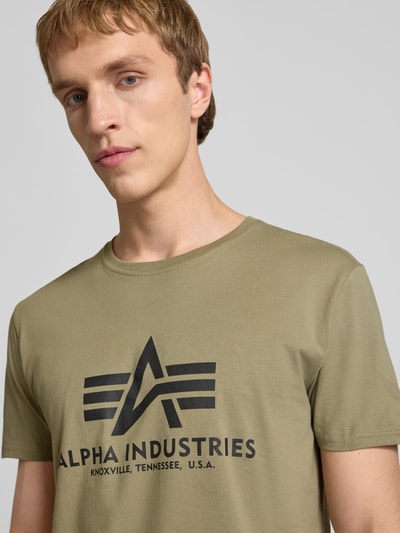 Männermodel trägt T-Shirt mit Logo und Rundhalsausschnitt von Alpha Industries in Olivgrün, reine Baumwolle, Regular Fit, Nahaufnahme Oberkörper