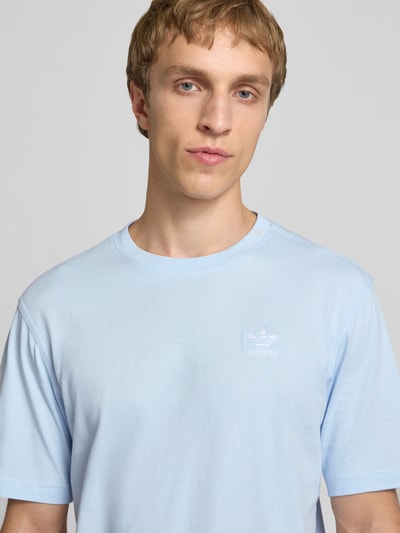Männermodel trägt Regular Fit T-Shirt aus reiner Baumwolle von adidas Originals, hellblau, kurzarm, Rundhals, Label Stitching, Nahaufnahme Oberkörper.