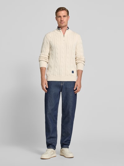 Männermodel trägt Strickpullover mit Stehkragen und Reißverschluss von PAUL SMITH aus reiner Baumwolle, Slim-Fit, cremefarben, Ganzkörperansicht von vorne.