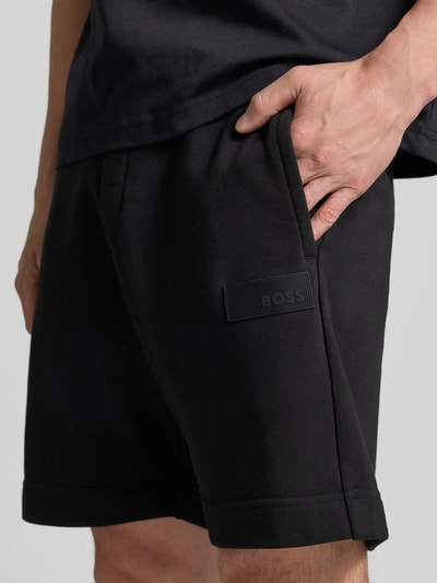 Männermodel trägt schwarze Regular Fit Sweatshorts aus Baumwoll-Mix Modell 'JT_SHORTS' von BOSS Green, Nahaufnahme Oberschenkel.