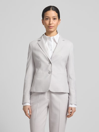 Modelka kobieca nosi Slim Fit Blazer mit Reverskragen von More & More, jasnoszary, tkanina z domieszką wiskozy, guziki, pasplowane kieszenie, krój slim fit, długość pleców w rozmiarze 36: 57 cm, szerokość w rozmiarze 36: 46 cm, długość rękawa w rozmiarze 36: 64 cm, widok całej sylwetki z przodu.