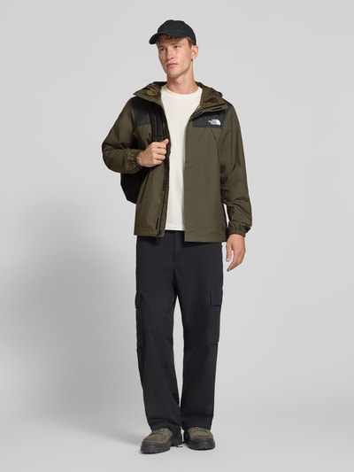 Männermodel trägt Jacke mit Label-Print Modell 'ANTORA' von The North Face in Olive, schwarze Details, Reißverschlusstaschen, Ganzkörperansicht von vorne. Rückenlänge, Schulterbreite, Brustweite und Ärmellänge entsprechen Größe M.