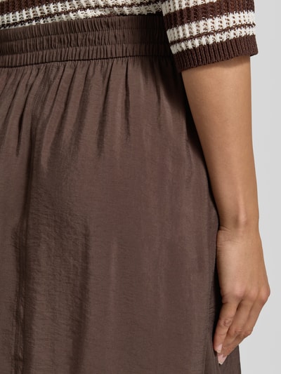 Frauenmodel trägt Midirock aus Modal-Mix Modell 'Ronella' von OPUS in Braun mit elastischem Bund, texturierte Oberfläche, Nahaufnahme Oberkörper, Kontext: Damen Midirock, A-Linie, Bundweite 36 cm, Gesamtlänge 80 cm.