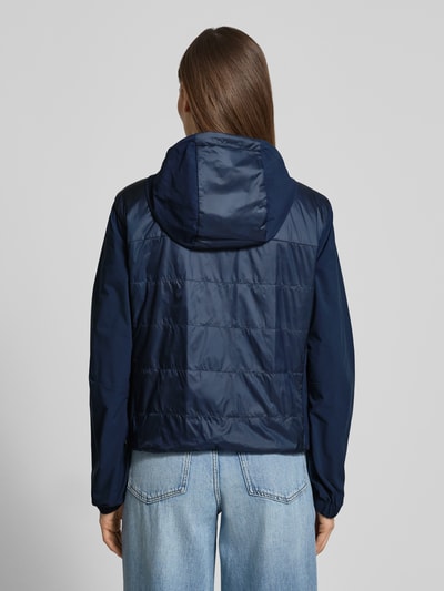 Frauenmodel trägt Jacke mit Zweiwege-Reißverschluss Modell 'MARTA' von FIRE + ICE in Dunkelblau, glatte Textur, Ganzkörperansicht Rückansicht. Regular Fit, Kapuze mit Tunnelzug, Rückenlänge 57 cm, Schulterbreite 46 cm, Brustweite 53 cm, Ärmellänge 62 cm bei Größe 36.