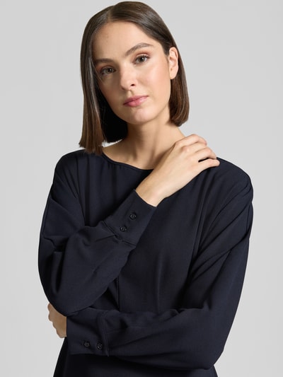Frauenmodel trägt Midikleid mit Rundhalsausschnitt von Christian Berg Woman Selection in dunklem Blau, fließender Stoff, glatte Textur, lange Ärmel, Kontext: A-Linie, Teilungsnaht, rückseitiger Reißverschluss, Rückenlänge 110 cm, Brustweite 39 cm, Ärmellänge 62 cm, Nahaufnahme Oberkörper.
