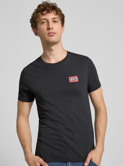 Männermodel trägt schwarzes Slim Fit T-Shirt-Set aus reiner Baumwolle im 2er-Pack von Levi's®, rote Logo-Details, Nahaufnahme Oberkörper.